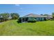 Backyard view of the home, featuring a screened lanai, and a pristine lawn extending to the water at 717 Manchester Woods Dr # 717, Sun City Center, FL 33573