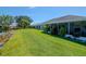 A beautifully manicured backyard with lush green grass, tropical plants, and a screened lanai overlooking a serene pond at 717 Manchester Woods Dr # 717, Sun City Center, FL 33573