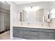 Bathroom with double sinks, gray vanity, and framed mirrors. The shower is enclosed with glass at 717 Manchester Woods Dr # 717, Sun City Center, FL 33573