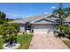 Charming single-story home with a brick driveway, an attached two-car garage, and beautiful tropical landscaping at 717 Manchester Woods Dr # 717, Sun City Center, FL 33573