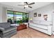 Cozy living room featuring a large window with blinds, hardwood floors, and neutral-toned sofa and sitting chair at 717 Manchester Woods Dr # 717, Sun City Center, FL 33573