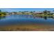 Tranquil pond view with reflections of neighborhood homes under a clear, sunny sky at 717 Manchester Woods Dr # 717, Sun City Center, FL 33573