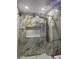 Bathroom with marble tiled walls, rainfall shower head, and decorative shelf at 7321 W Pocahontas Ave, Tampa, FL 33634