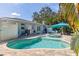 Lush backyard with a swimming pool, hot tub, patio area, and cozy seating under a turquoise umbrella, creating a relaxing oasis at 8200 31St N Ter, St Petersburg, FL 33710