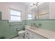 Well-lit bathroom with green tile, a window, and a stylish vanity featuring a marble countertop and ample storage at 8200 31St N Ter, St Petersburg, FL 33710