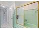 Bathroom featuring a walk-in shower with glass doors, green tile, white trim, and a glimpse into the adjacent hallway at 8200 31St N Ter, St Petersburg, FL 33710