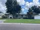 Well-kept home with a green lawn, pretty landscaping, and a cute pink door and shutters at 8211 Diagonal N Rd, St Petersburg, FL 33702