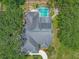 Aerial view showcases a private pool with screened enclosure, solar panels, and lush landscaping enhancing outdoor living at 8711 Crescent Forest Blvd, New Port Richey, FL 34654
