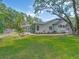 Large backyard with mature trees, lush lawn, landscaping, and the screened-in pool visible in the background at 8711 Crescent Forest Blvd, New Port Richey, FL 34654