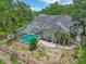 Aerial view showcases a private pool with screened enclosure, solar panels, and lush landscaping enhancing outdoor living at 8711 Crescent Forest Blvd, New Port Richey, FL 34654
