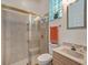 Bathroom with glass shower doors, stone tile, and a glass block window for natural light and privacy at 8711 Crescent Forest Blvd, New Port Richey, FL 34654