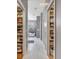 Hallway with white tile flooring leads to the bathroom with a soaking tub and organized closet spaces at 8711 Crescent Forest Blvd, New Port Richey, FL 34654
