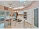 Bright kitchen with a center island cooktop, white cabinets, stainless steel appliances, and an adjacent breakfast area with pool view at 8711 Crescent Forest Blvd, New Port Richey, FL 34654