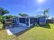 Backyard with green grass, mature trees, and a screened porch with patio seating at 8848 56Th N Way, Pinellas Park, FL 33782