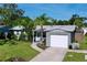 Home exterior featuring a well-manicured lawn, mature trees, and attached one car garage at 8848 56Th N Way, Pinellas Park, FL 33782