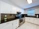 Modern kitchen featuring white cabinetry, stainless steel appliances, black subway tile backsplash, and light hardwood flooring at 8848 56Th N Way, Pinellas Park, FL 33782