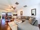Cozy living room with white brick walls, a large sectional sofa, hardwood floors, and a view into the kitchen at 8848 56Th N Way, Pinellas Park, FL 33782