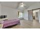 Bedroom with light wood floor, ceiling fan, and a barn door leading to the bathroom at 9041 58Th N St, Pinellas Park, FL 33782