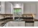 Close-up of the kitchen sink with white cabinets, granite counters, and mosaic backsplash detailing at 9041 58Th N St, Pinellas Park, FL 33782