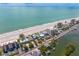 Stunning aerial view of beachfront homes, a beautiful white sand beach, and clear blue ocean waters at 20060 Gulf Blvd, Indian Shores, FL 33785
