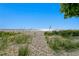 Scenic beach view framed by native grasses leading to a clear blue ocean under a sunny sky at 20060 Gulf Blvd, Indian Shores, FL 33785