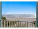 Balcony view featuring white railings with beach, green plant life, and beautiful ocean view in the background at 20060 Gulf Blvd, Indian Shores, FL 33785