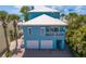 Captivating exterior view of a blue two-story beach house with a metal roof, porch, and two-car garage at 20060 Gulf Blvd, Indian Shores, FL 33785