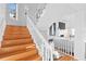 Bright and inviting staircase entry featuring hardwood floors, a white banister, and decorative lighting at 20060 Gulf Blvd, Indian Shores, FL 33785