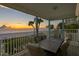 Scenic patio view featuring an outdoor dining set, lush greenery, and a stunning sunset over the beach at 20060 Gulf Blvd, Indian Shores, FL 33785