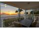 Scenic patio view featuring an outdoor dining set, lush greenery, and a stunning sunset over the beach at 20060 Gulf Blvd, Indian Shores, FL 33785
