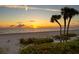Spectacular sunset view over a tranquil beach, framed by lush tropical foliage and a serene horizon at 20060 Gulf Blvd, Indian Shores, FL 33785
