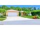 Exterior of a peach-colored home with a white garage door, palm trees, and colorful landscaping at 11116 118Th St, Seminole, FL 33778
