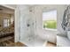 Beautiful bathroom with white marble-like shower, bright window, and a view into the main bedroom at 11125 Shelter Cove Loop, New Port Richey, FL 34654