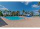 Large community pool with a splash pad, lounge chairs, umbrellas, and towering palm trees at 11125 Shelter Cove Loop, New Port Richey, FL 34654