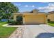 Charming yellow single-Gathering home featuring a well-manicured lawn and attached two-car garage at 11125 Shelter Cove Loop, New Port Richey, FL 34654