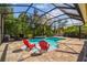Screened in pool with ample deck space, lounge chairs, and waterfall feature at 11125 Shelter Cove Loop, New Port Richey, FL 34654
