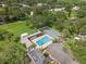 Aerial view of a community pool with shuffleboard courts surrounded by lush greenery at 1136 Thayer St, Safety Harbor, FL 34695