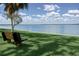 Serene waterfront view with a bench on lush grass, inviting relaxation by the water at 1136 Thayer St, Safety Harbor, FL 34695