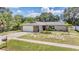 Aerial view of a well-kept home with stone accents, a spacious driveway, and a manicured lawn at 1403 Tallahassee Dr, Tarpon Springs, FL 34689