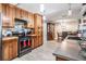 Kitchen with wooden cabinets, black appliances, and an open view to the dining area at 1403 Tallahassee Dr, Tarpon Springs, FL 34689