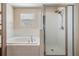 Bathroom featuring a white-tiled soaking tub and a glass-enclosed shower, alongside neutral wall colors, offering relaxation at 15420 Quail Woods Pl, Ruskin, FL 33573
