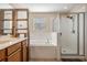 Primary bathroom showcasing a dual sink vanity, a soaking tub, and a glass-enclosed shower, featuring tiled walls at 15420 Quail Woods Pl, Ruskin, FL 33573