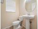 Half bathroom featuring a modern toilet, and a pedestal sink with chrome fixtures, complemented by a window for natural light at 15420 Quail Woods Pl, Ruskin, FL 33573