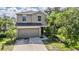 Two-story home featuring a large garage, well-kept lawn, and tropical landscaping at 15420 Quail Woods Pl, Ruskin, FL 33573