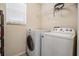 A laundry room with a washer, dryer, shelves and a window with blinds at 15420 Quail Woods Pl, Ruskin, FL 33573