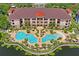 Aerial view of a modern condo complex, showcasing a large pool and landscaped grounds with palm trees on a sunny day at 1640 Villa Capri Cir # 206, Odessa, FL 33556