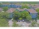 Aerial view of blue apartment buildings with brown roofs, surrounded by mature trees and a parking lot at 1640 Villa Capri Cir # 206, Odessa, FL 33556