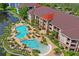 An elevated view of the community pool area with palm trees, lush green landscaping, and inviting lounge chairs at 1640 Villa Capri Cir # 206, Odessa, FL 33556