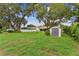 Lush backyard featuring green lawn, large trees and a storage shed at 1810 Tamerlane Pl, Brandon, FL 33510