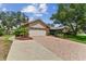 Paver driveway and two car garage of charming single-story home surrounded by lush landscaping and mature trees at 1810 Tamerlane Pl, Brandon, FL 33510